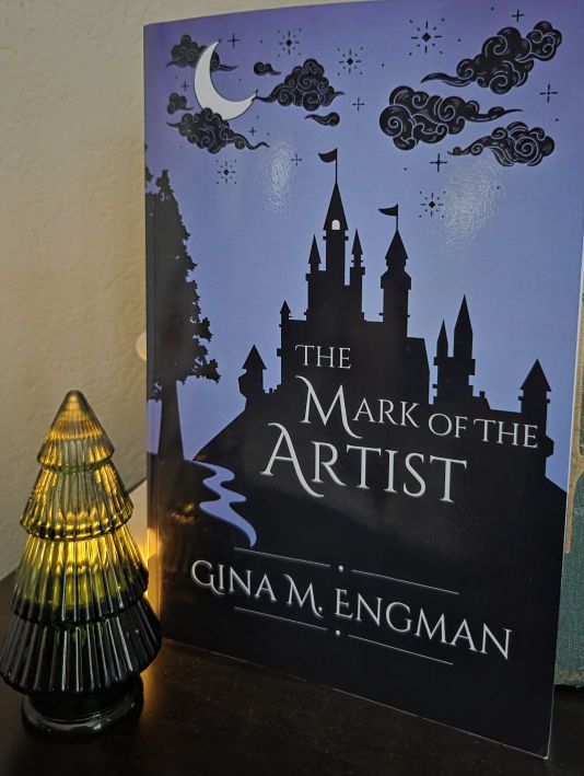 The Mark of the Artist paperback next to a glass Christmas tree